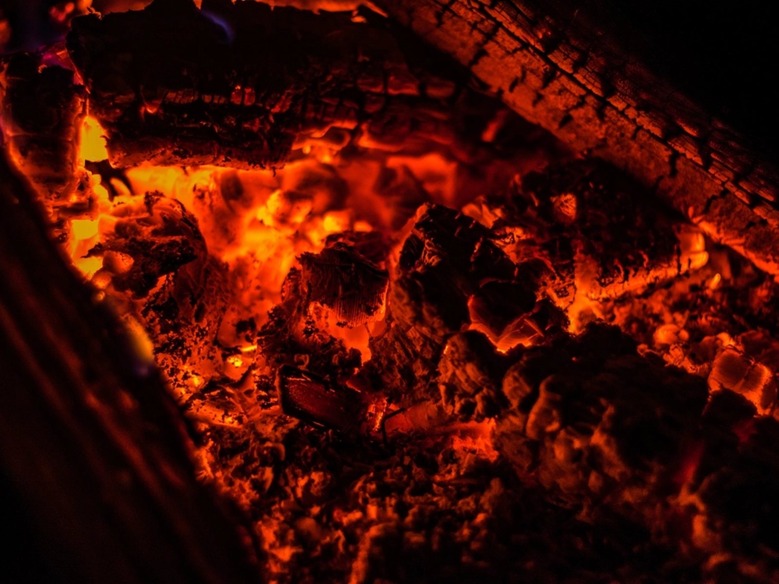 Embers banked in a forge, orange heat showing through a dark crust